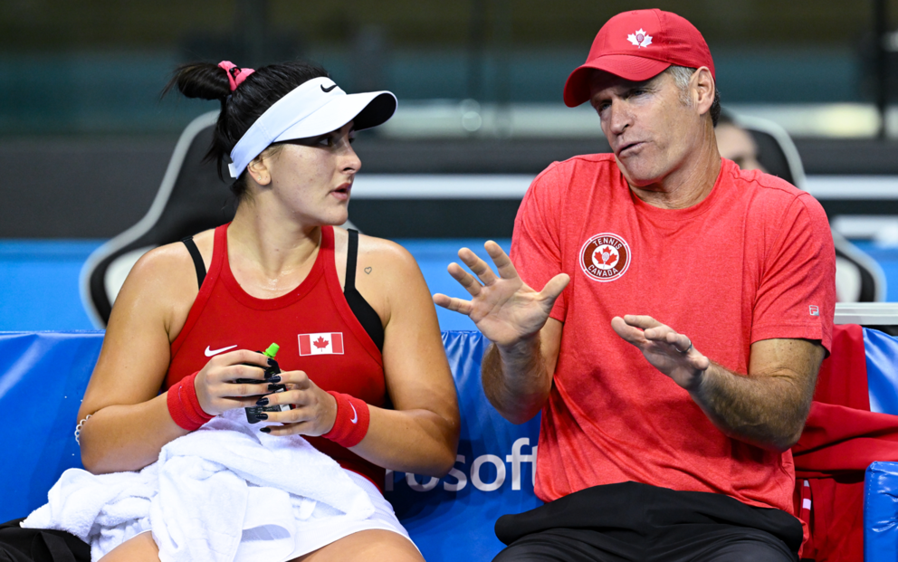 Sylvain Bruneau (right) gives Bianca Andreescu coaching while gesturing with his hands on the bench,