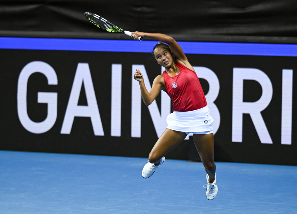Leylah Fernandez leaps into the air following through on a backhand.