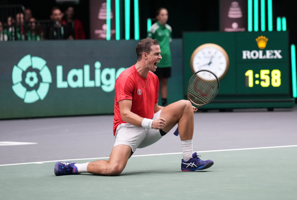 Vasek Pospisil kneels on the court, pumps his fist and shouts.