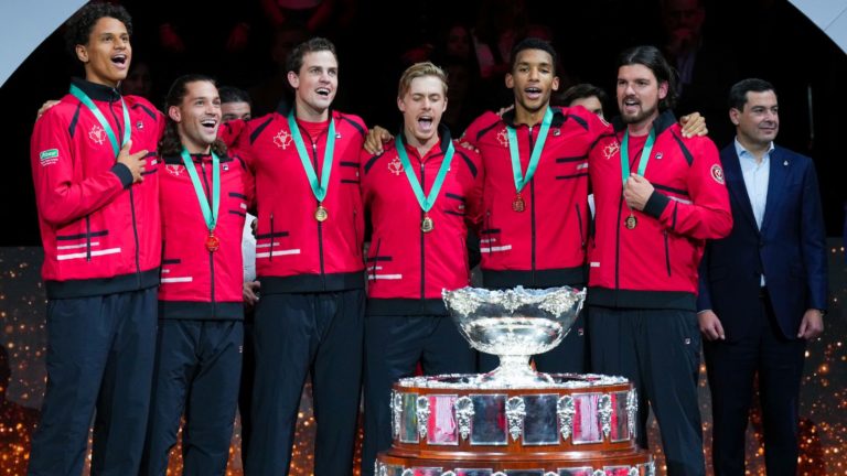 From left to right, Gabriel Diallo, Alexis Galarneau, Vasek Pospisil, Denis Shapovalov, Felix Auger-Aliassime and Frank Dancevic stand behind the Davis Cup trophy and sing O Canada