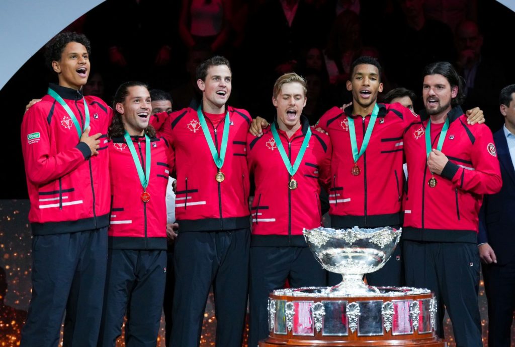 From left to right, Gabriel Diallo, Alexis Galarneau, Vasek Pospisil, Denis Shapovalov, Felix Auger-Aliassime and Frank Dancevic stand behind the Davis Cup trophy and sing O Canada