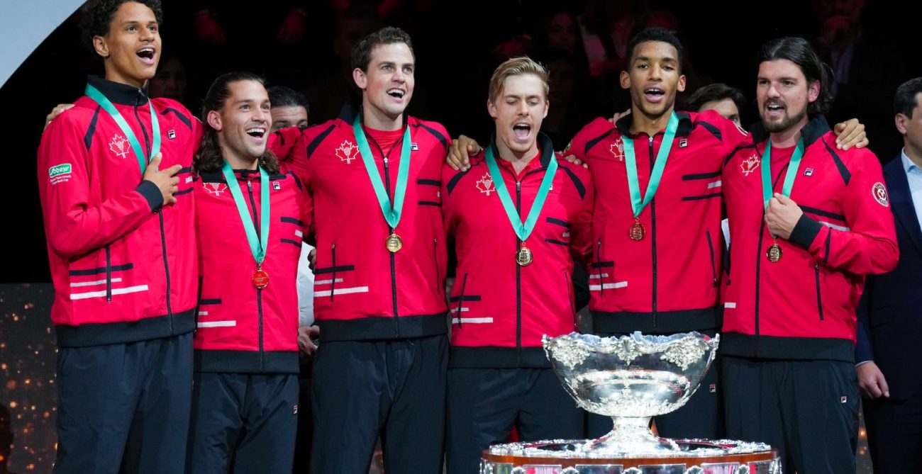 From left to right, Gabriel Diallo, Alexis Galarneau, Vasek Pospisil, Denis Shapovalov, Felix Auger-Aliassime and Frank Dancevic stand behind the Davis Cup trophy and sing O Canada