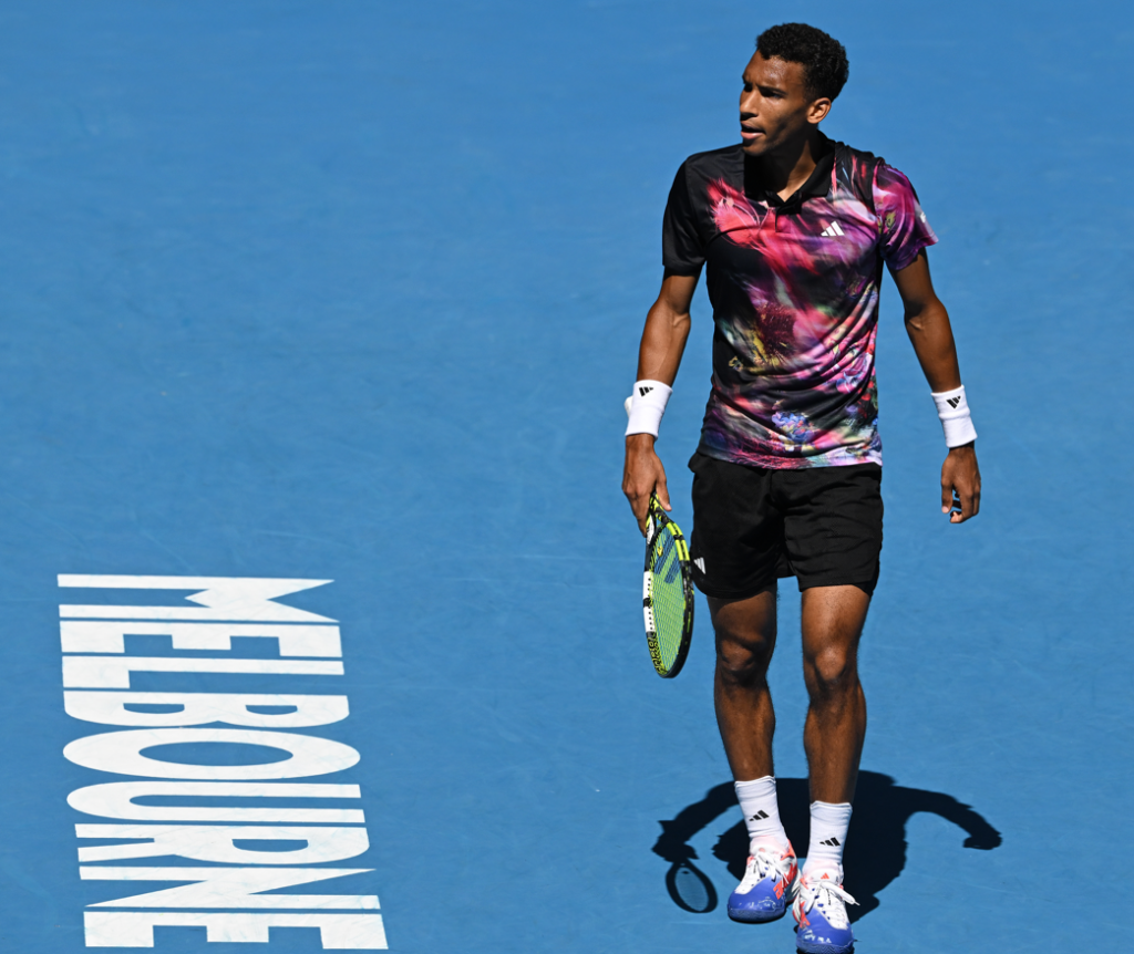 Felix Auger-Aliassime walks behind the Melbourne logo on the court.