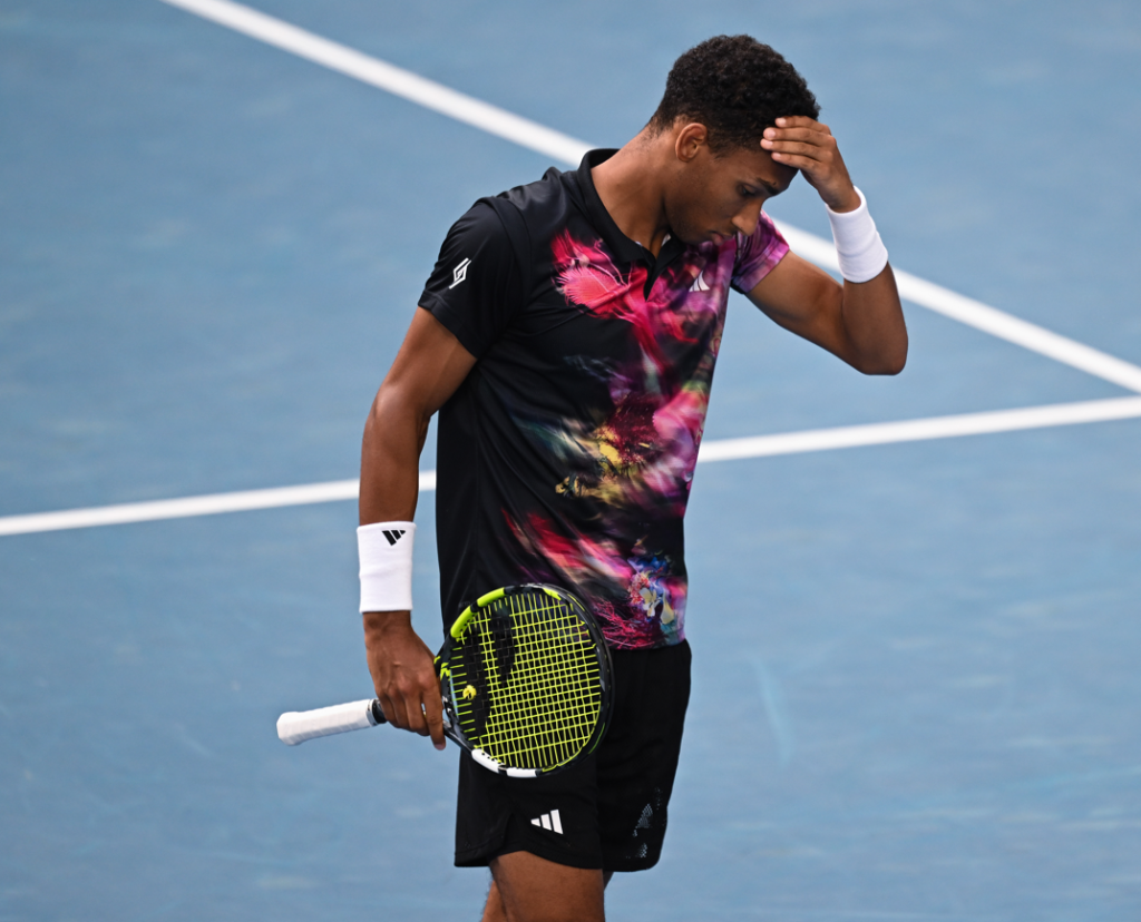 Felix Auger-Aliassime looks down and puts his hand on his head in frustration.