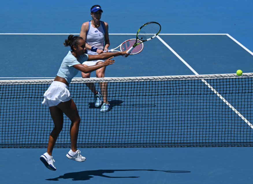 Leylah Annie Fernandez lunges for a volley at the net while Alize Cornet looks on from the other side of the net.
