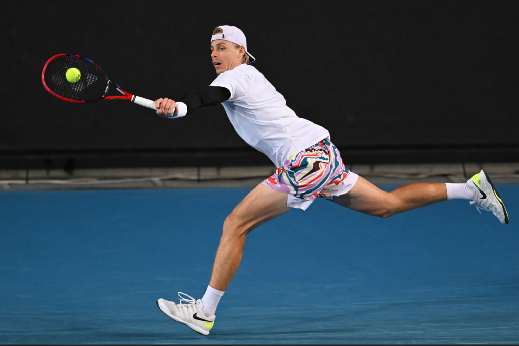 Denis Shapovalov lunges to hit a backhand.
