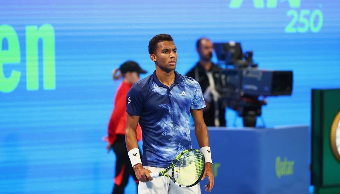 Felix Auger-Aliassime stands and looks across the court.