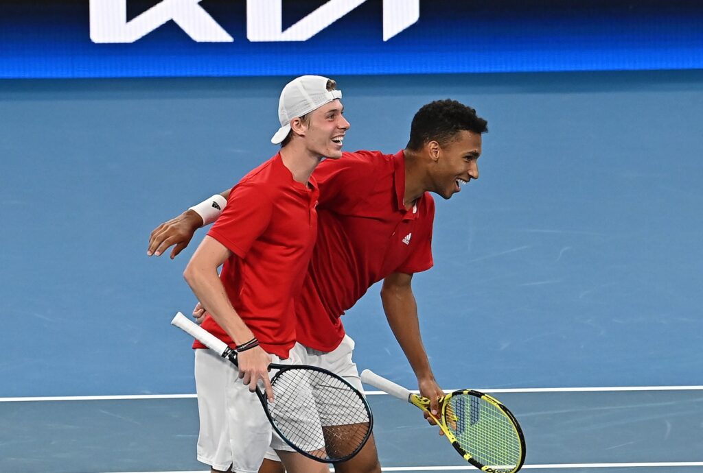 Denis Shapovalov and Felix Auger-Aliassime half embrace and smile.