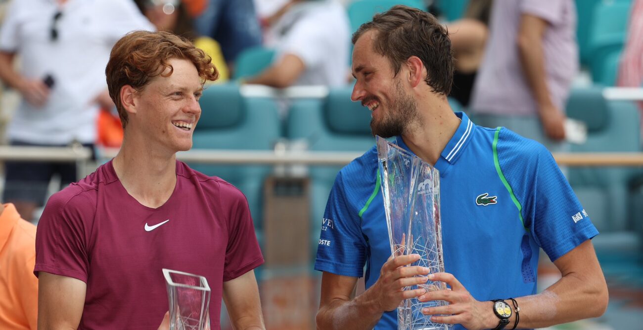 Jannik Sinner (left) and Daniil Medvedev look at each other and smile while holding their Miami trophies.