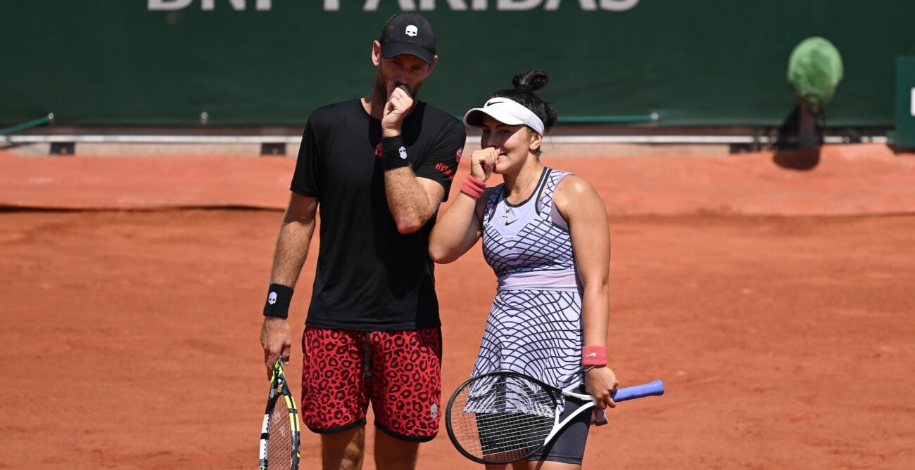 Bianca Andreescu (right) and Michael Venus lean close and cover their mouths as they strategize.
