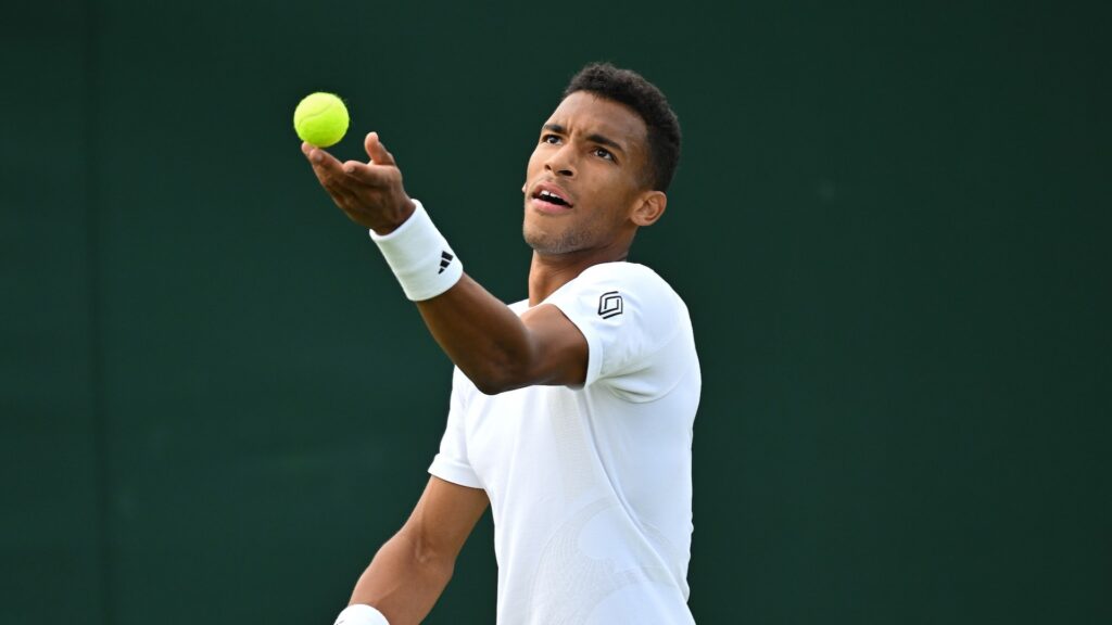 Felix Auger-Aliassime tosses a ball up to serve.