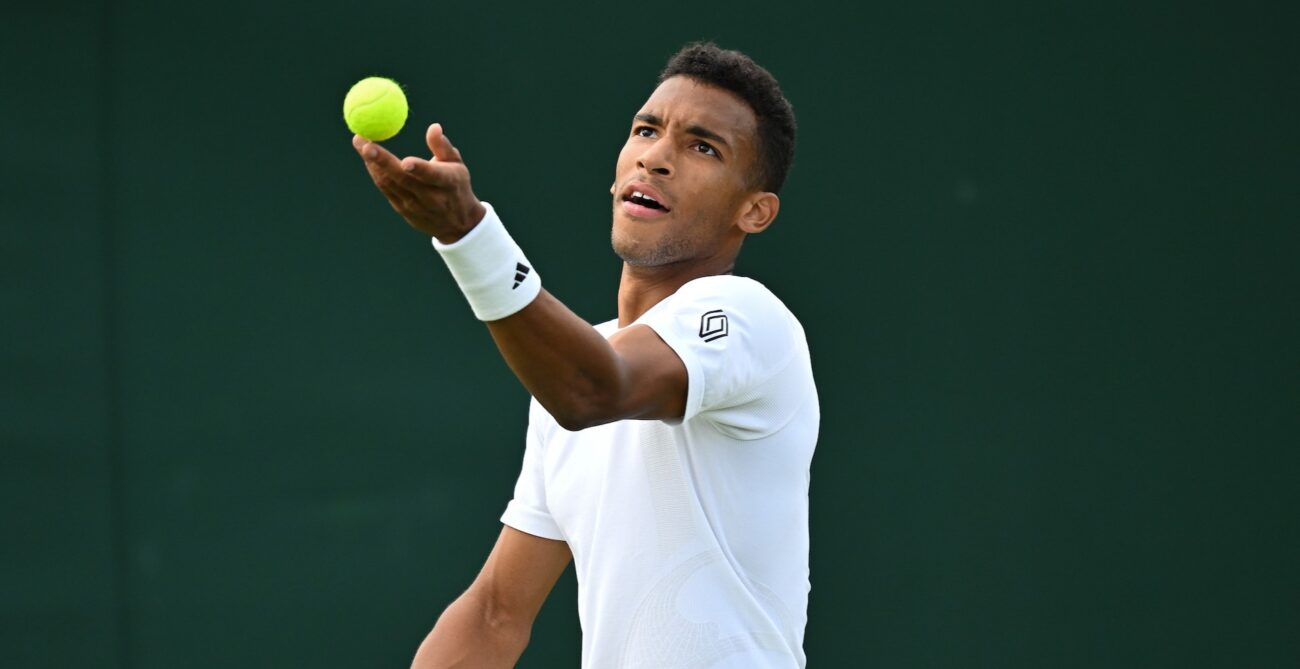 Felix Auger-Aliassime tosses a ball up to serve.
