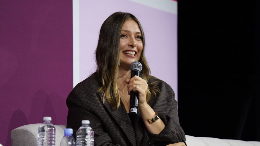 Maria Sharapova holds a microphone and smiles.