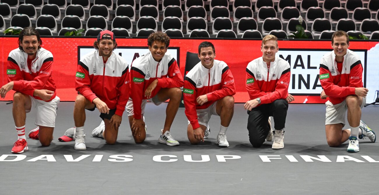 From left to right, Frank Dancevic, Kelsey Stevenson, Gabriel Diallo, Alexis Galarneau, Denis Shapovalov, and Vasek Pospisil kneel over the Davis Cup Finals sign.