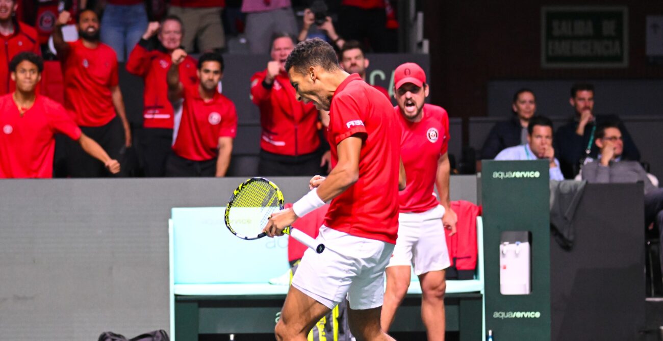 Felix Auger-Aliassime pumps his fist with Frank Dancevic and Team Canada cheering in the background at the Davis Cup.