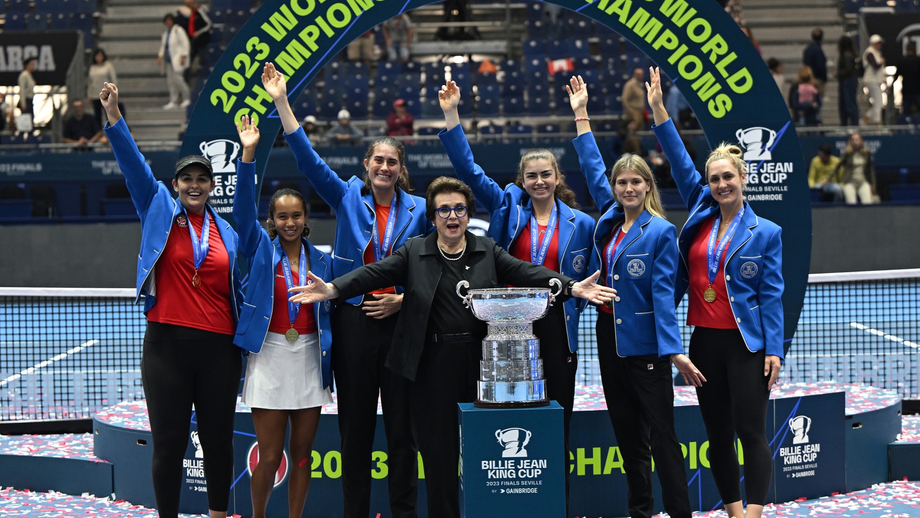 Team Canada celebrates on-court behind the trophy with Billie Jean King.