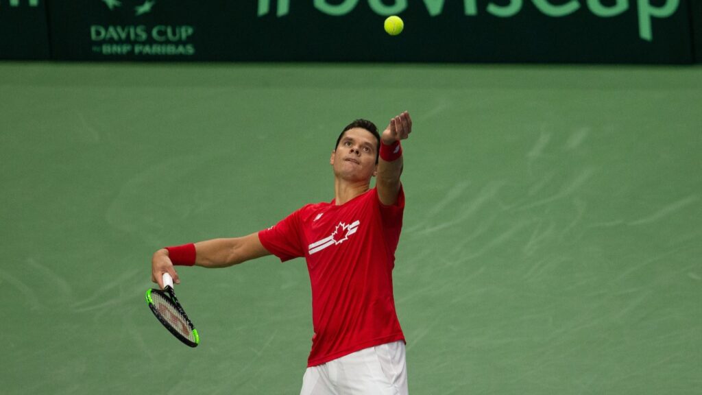 Milos Raonic tosses a ball up to serve while playing for Team Canada at the Davis Cup.