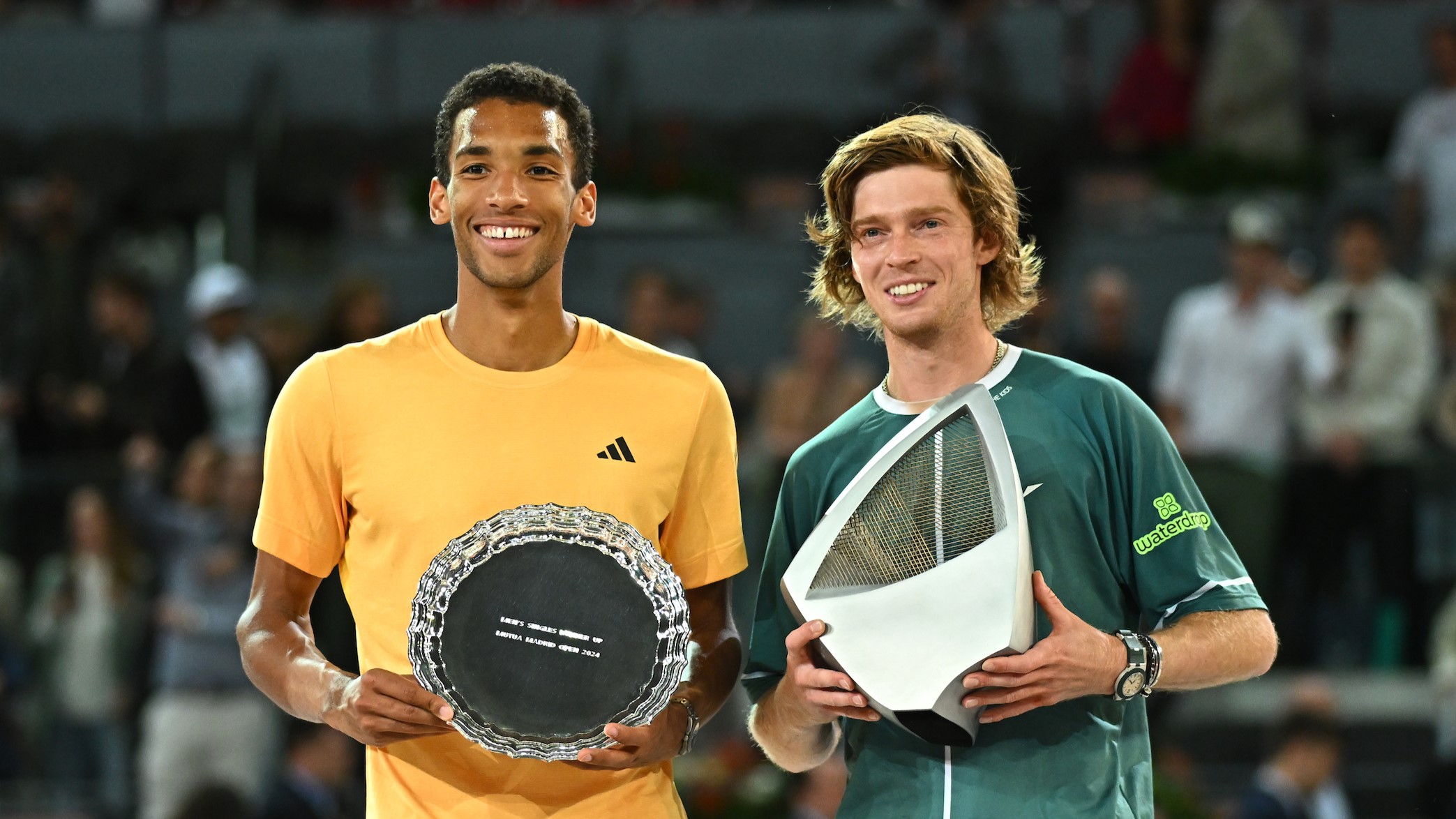 Felix Auger-Aliassime (left) holds up his runner-up trophy and smiles next to Andrey Rublev, holding his champions trophy in Madrid.